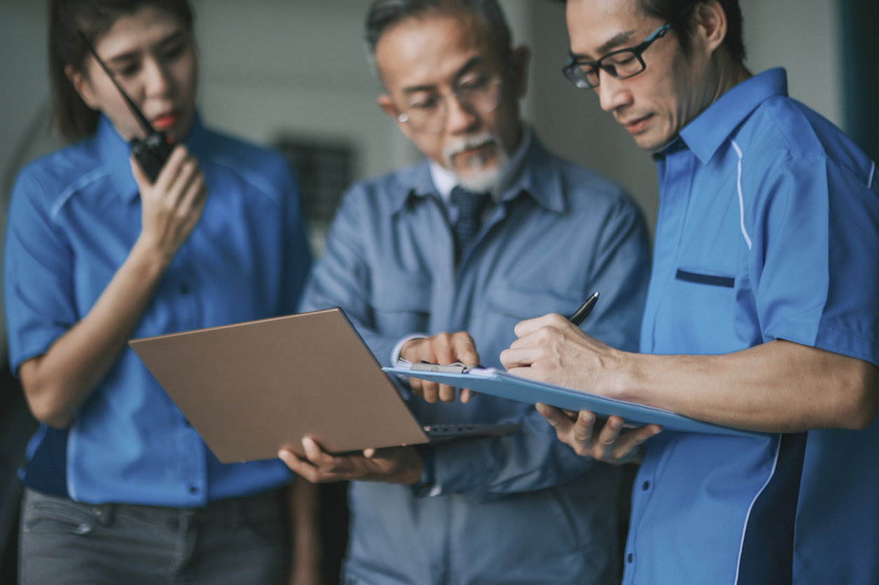 Asian Chinese factory manager working with his team in warehouse on checklist and shipment order in warehouse