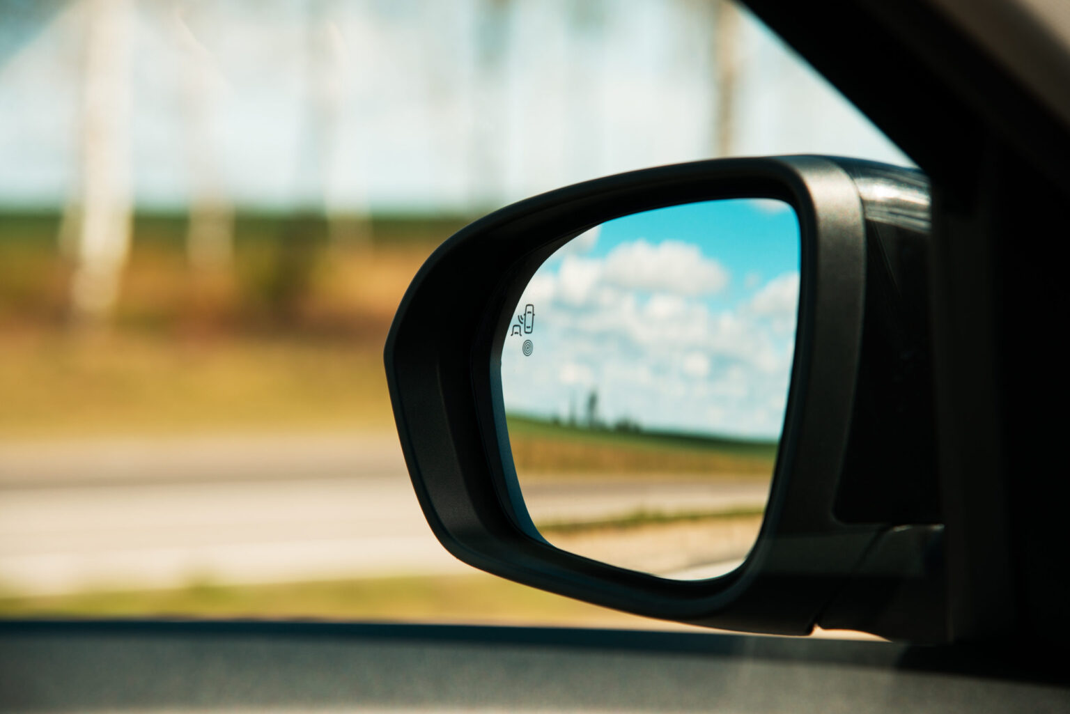 A blind spot monitoring sensor on the side mirror of a modern car.