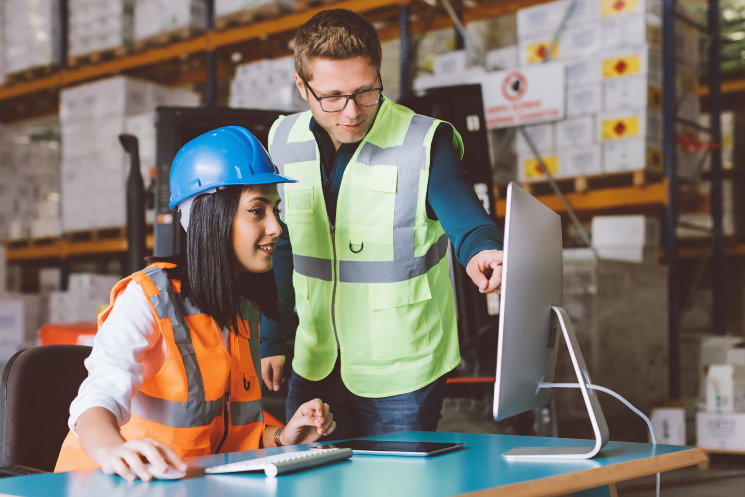 Young warehouse worker businessman and businesswoman working and looking at tablet and desk computer in a interior of large warehouse. XXXL size taken with Canon 5d M4 - 2017