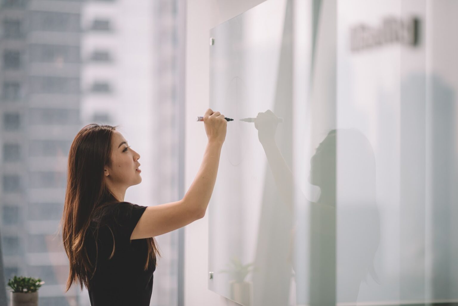 an asian chinese female writing on white board with her marker pen during conference meeting in office conference room