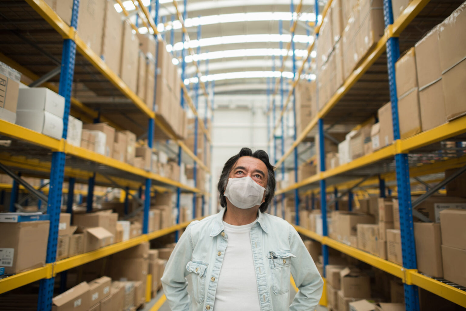 Thoughtful man working at a warehouse wearing a facemask to avoid coronavirus Portrait of a thoughtful Latin American man working at a warehouse wearing a facemask to avoid coronavirus -pandemic lifestyle concepts