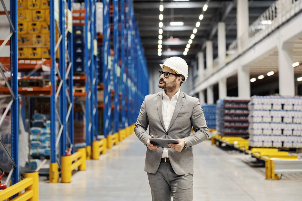 A supervisor using tablet to check on goods for shipment at warehouse.