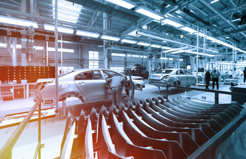 Worker looks into car body on production line. Factory for production of cars in blue. Modern automotive industry. Blue tone