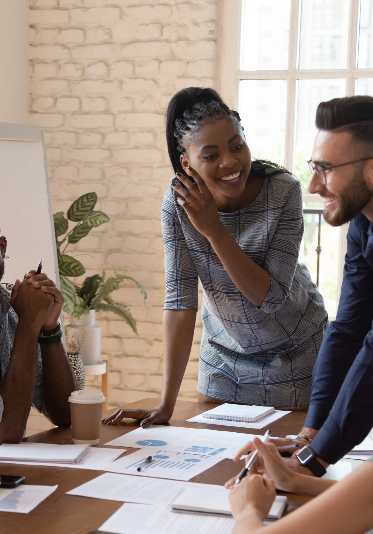 Happy friendly multiracial team laughing working together at corporate briefing Happy friendly multiracial business team laughing working together at corporate briefing gathered at table, cheerful diverse office people group having fun talking enjoy teamwork during staff meeting